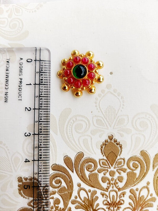 Multicolor floral statement earrings from Mugdha Jewellery Store, featuring a central green stone surrounded by vibrant red and gold petals against a neutral background.