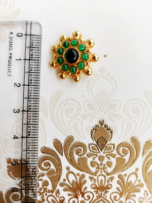 Elegant Peshwai green and gold flower earrings against a patterned white background with ruler for scale