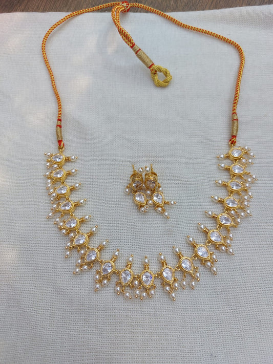 Elegant gold-toned Tanmani necklace with sparkling crystal embellishments, showcased on a light background.