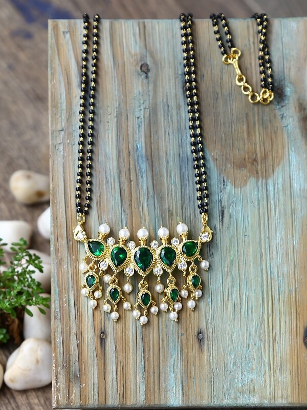 Elegant green stone mangalsutra with gold accents on a wooden background