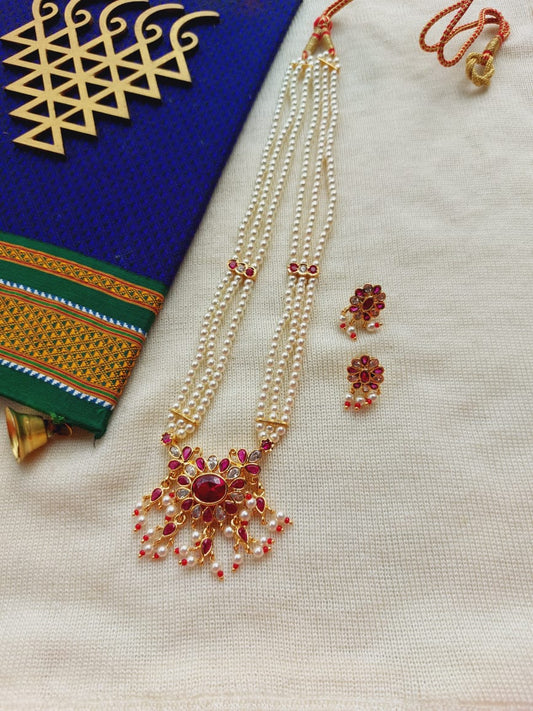 Elegant floral gold-tone necklace and earrings set on white cloth with vibrant ethnic patterns