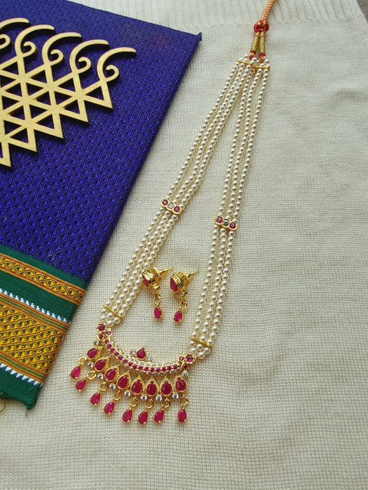 Gold and ruby designer maharani short haar necklace with matching earrings on a colorful patterned fabric.