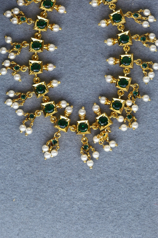 Elegant traditional jewelry set with green gemstones and pearls on gray background