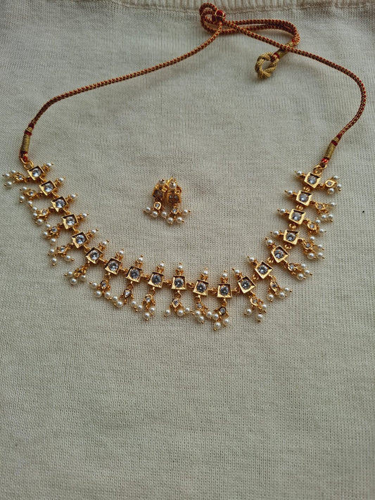 Elegant gold-toned necklace and ring set with sparkling rhinestones, displayed on a light gray background.