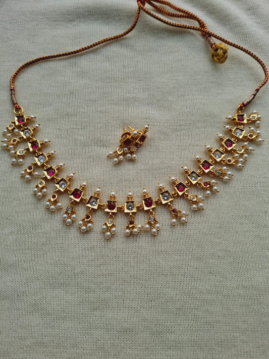 Beautiful gold and pink gemstone traditional designer necklace set on a plain background