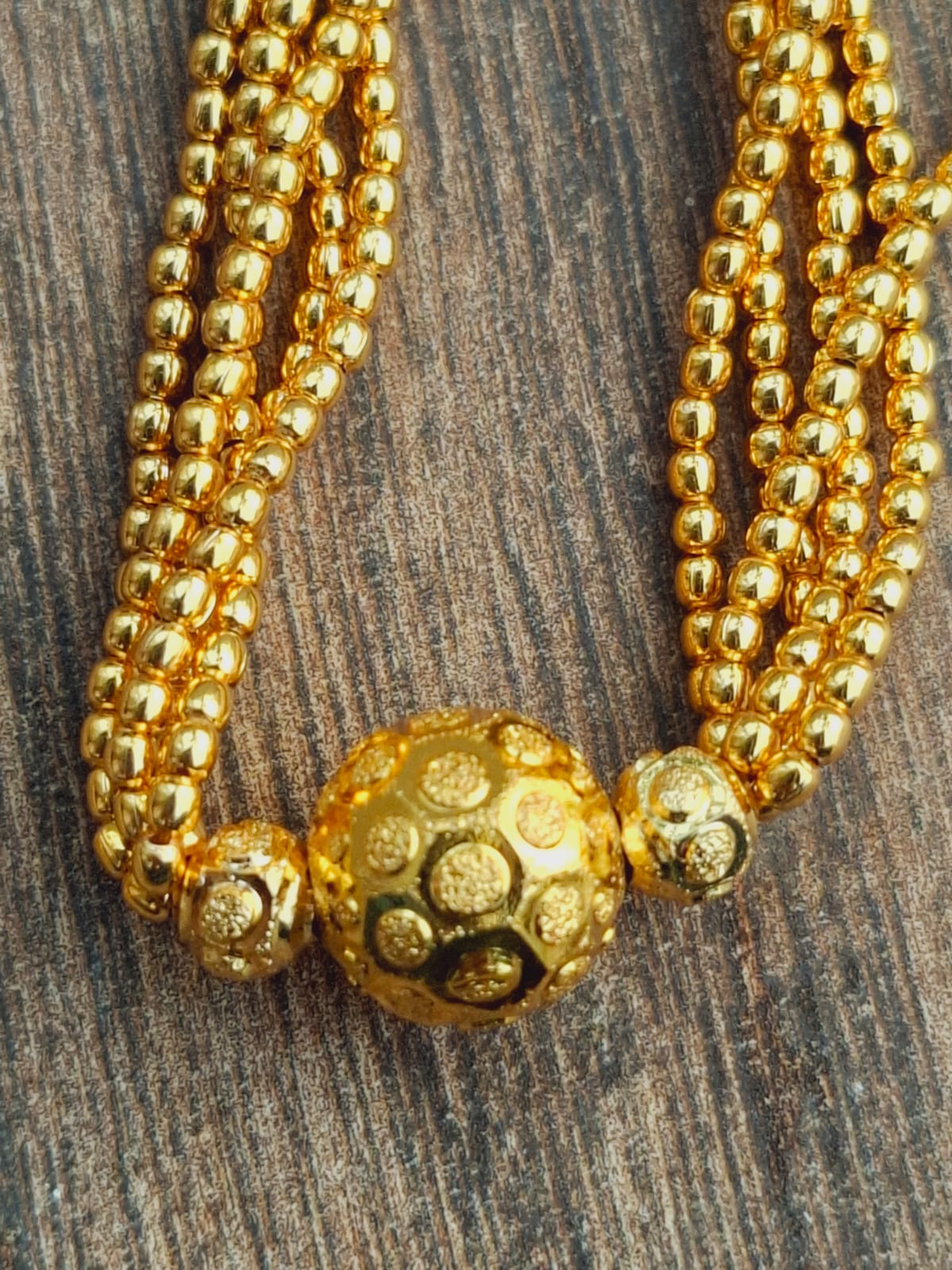Traditional Golden Bead Thushi Necklace - Elegant gold beaded necklace with intricate gold pendant on rustic wooden surface.